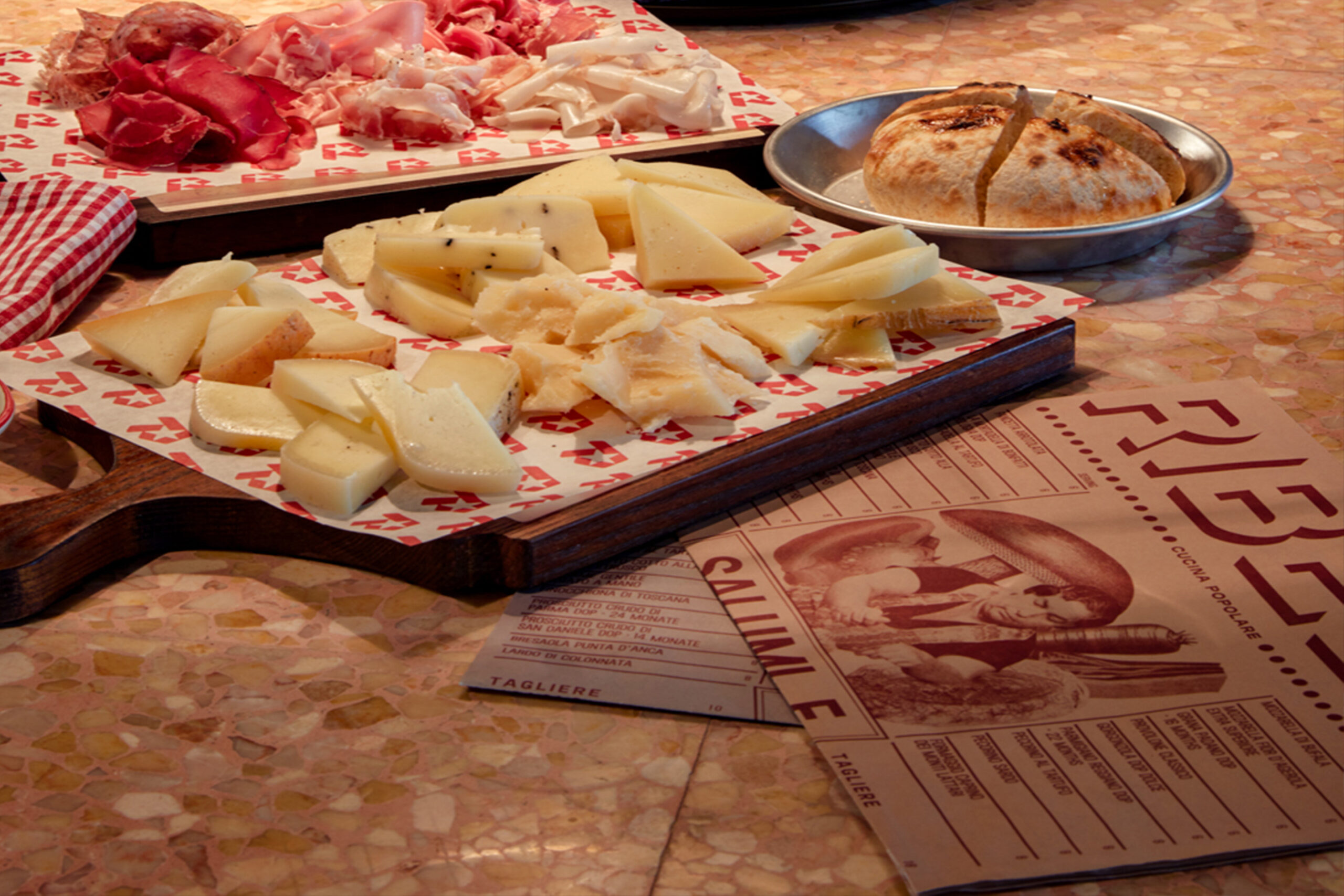 An assortement of different meat cuts and cheeses, as well as bread on different plates